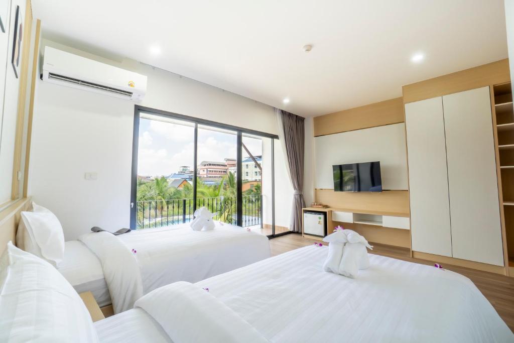 A twin bedroom with a balcony view toward nearby buildings and greenery.