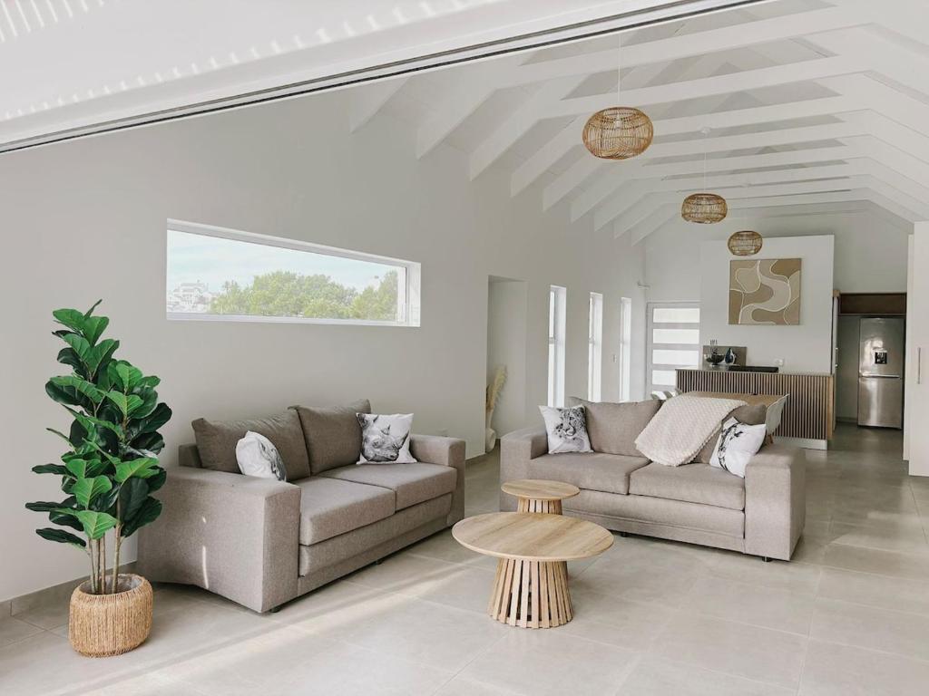 a living room with two couches and a table at Villa Jabulani in Stompneusbaai