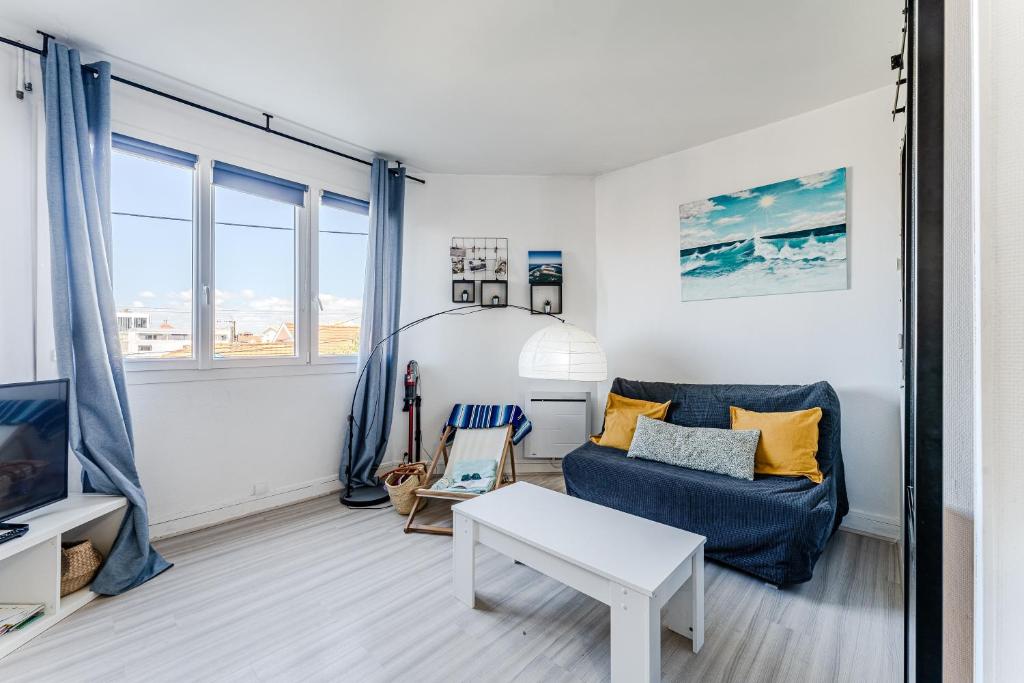 a living room with a blue couch and a table at Appartement Le Mauresque in Arcachon