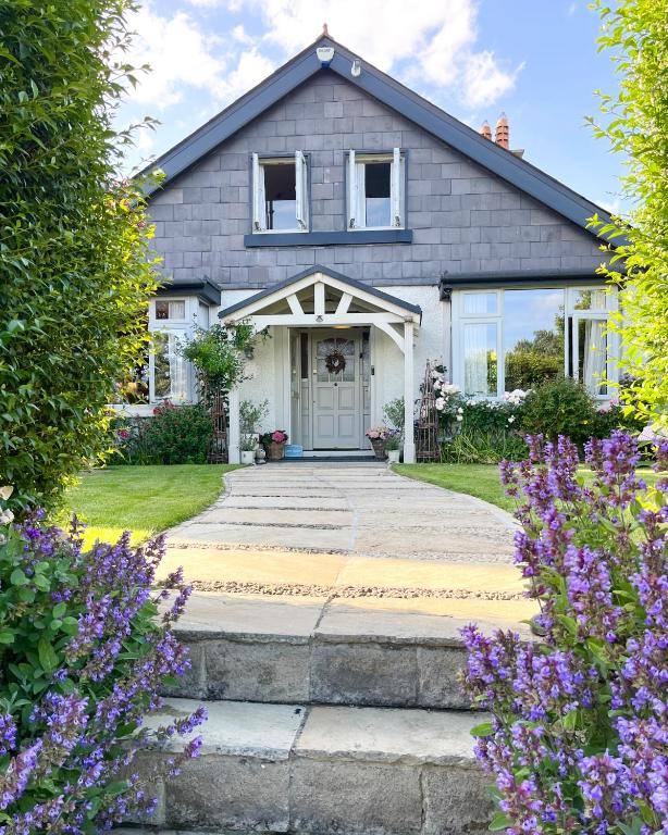 a house with a driveway and flowers in front of it at The Artist Residence Dublin Boutique B&B in Sutton