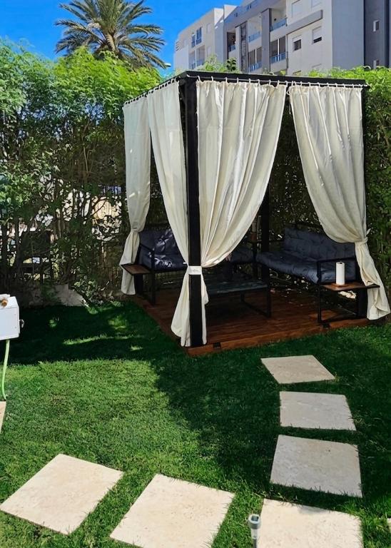a gazebo with a white curtain on the grass at Le Havre de Paix in Nabeul
