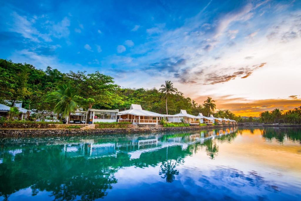 a resort on the water at sunset at Golden Sands Destination Resorts in Daanbantayan