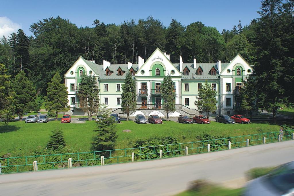 a large white house with cars parked in front of it at Pod Jodłą in Iwonicz-Zdrój