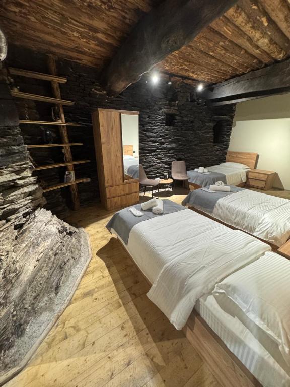 a bedroom with two beds and a stone wall at Firefly in Shatili