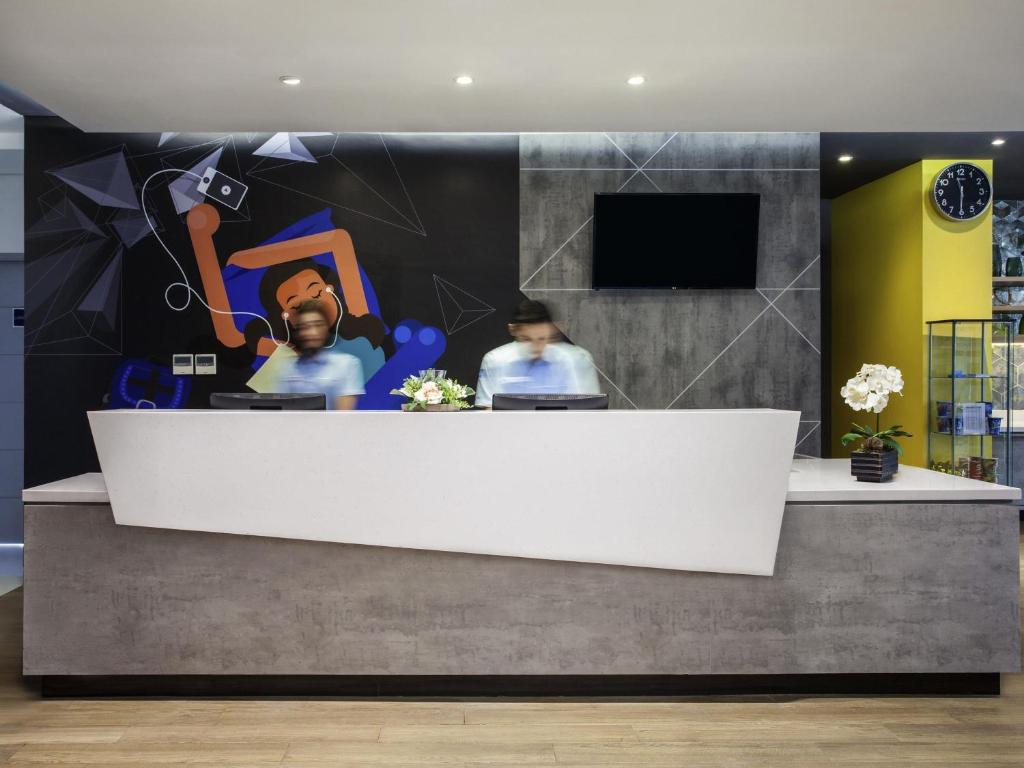 a reception desk with a mural of a man at ibis budget Surabaya Diponegoro in Surabaya