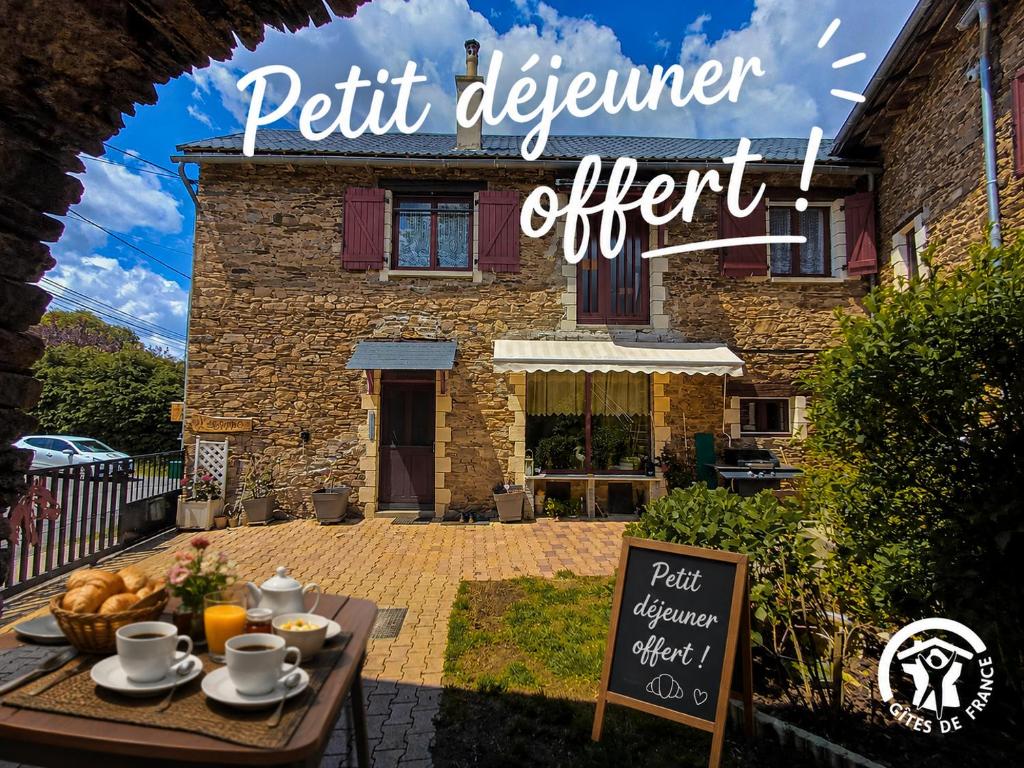 a sign in front of a house with a table with food at L'Escapade de JOS , chambres et table d'hôte in Pont-de-Salars