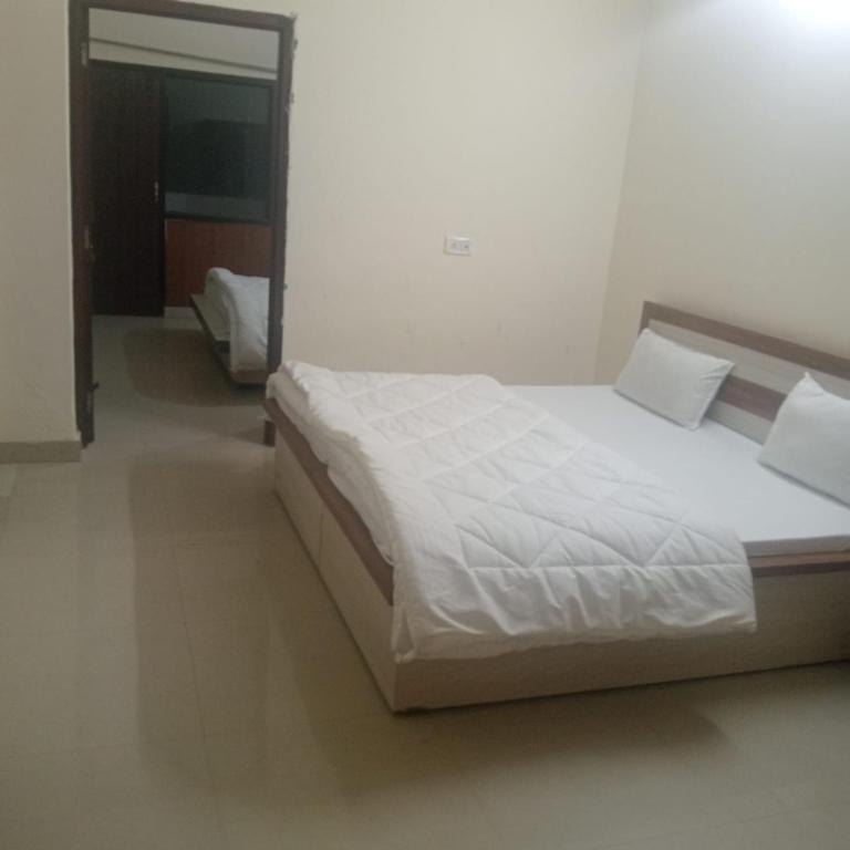 a large bed in a room with a white bed sidx sidx sidx at New Vybent Hotel Kainchi Dham in Bhowāli