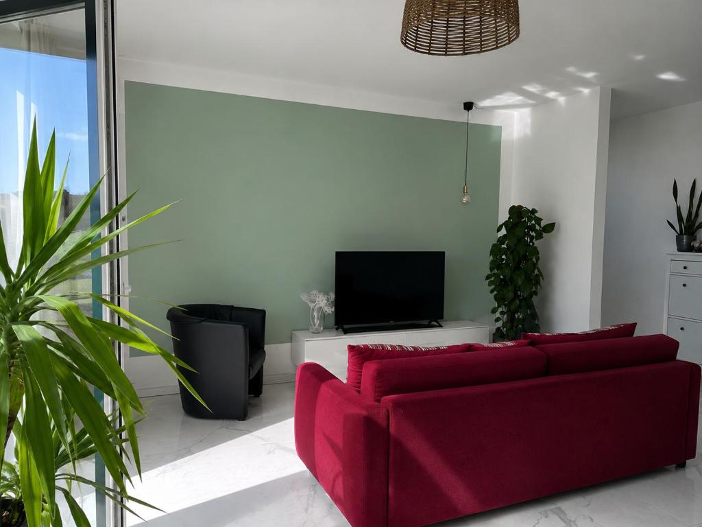 a living room with a red couch and a tv at Gemütliche Wohnung mit Terrasse im Grünen in Bienenbüttel