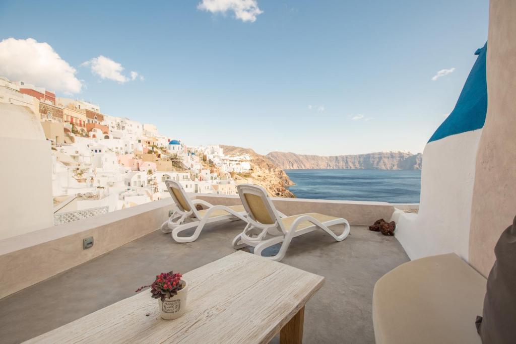 a balcony with a table and chairs and a view of a city at The Dream Santorini in Oia