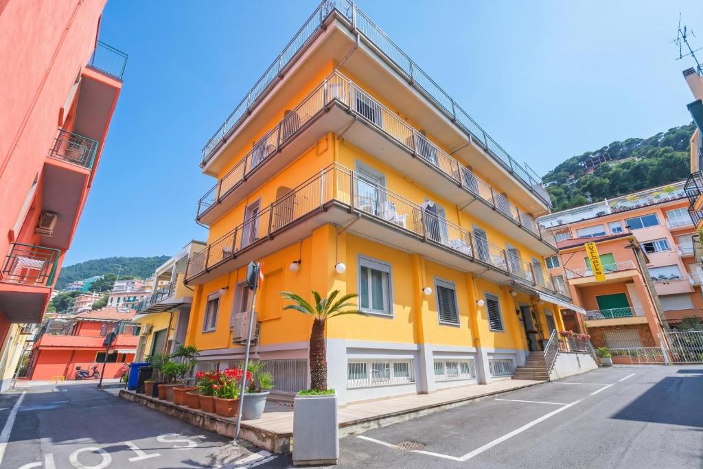 a yellow building with a palm tree in front of it at Hotel Del Golfo in Laigueglia