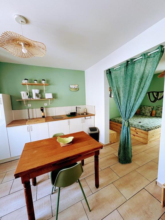 a kitchen with a wooden table and a bedroom at Le Temps d une Pause in Calais