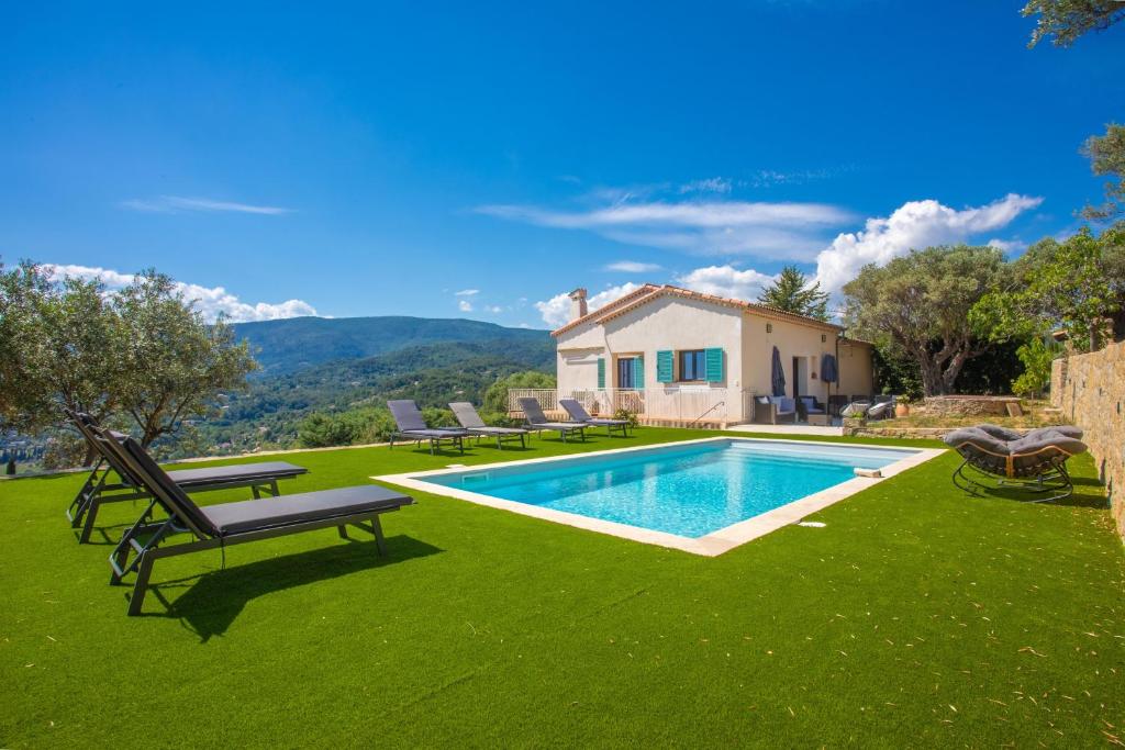 a backyard with a swimming pool and green grass at Les Oliviers De Lunéa in Fayence