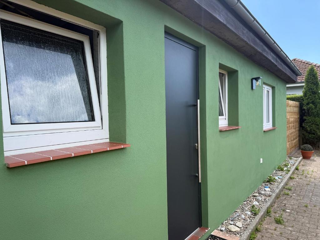 a green house with a window and a door at Strandoase in Grömitz
