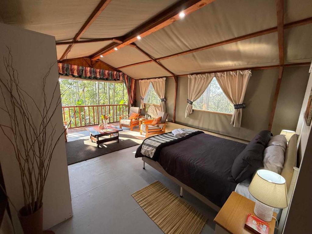 a bedroom with a bed and a living room at Kholiwe 1 - 4 sleeper glamping in a forest in Port Edward