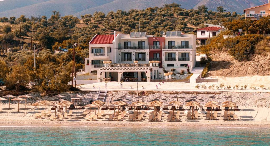 a large building on a beach with chairs and umbrellas at Acron Suites in Limenaria