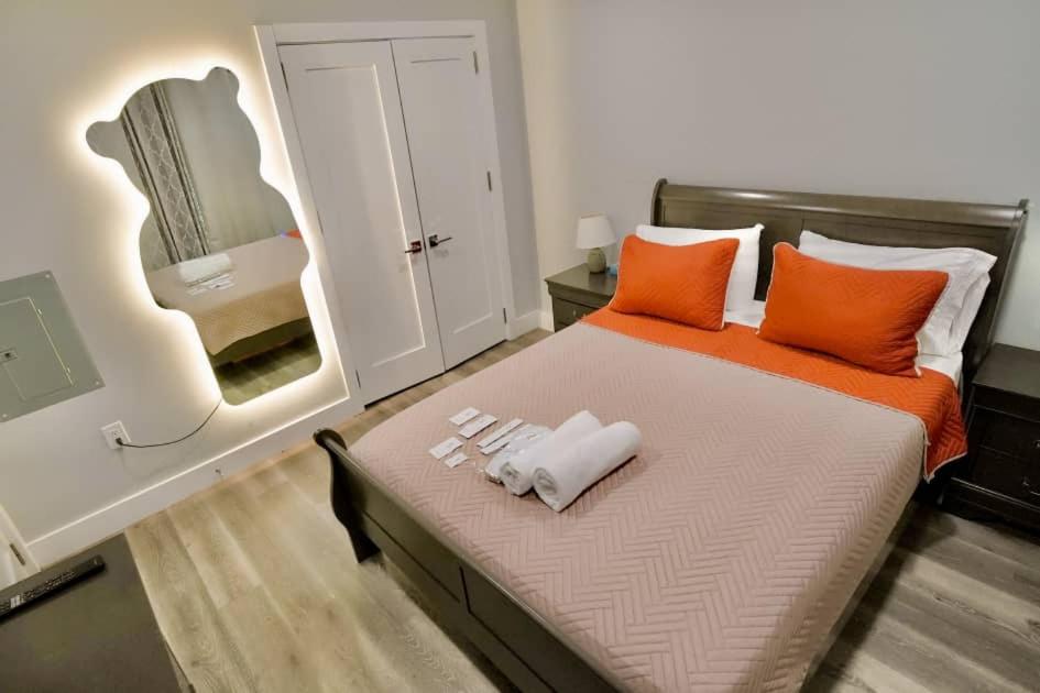 a bedroom with a bed with orange pillows and a mirror at The Lovely Suite - 1BR close to NYC in Paterson