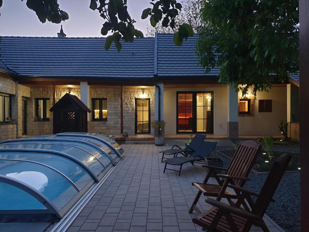 a patio with chairs and a swimming pool in front of a house at Tóparti Idill Vendégház in Kisszékely