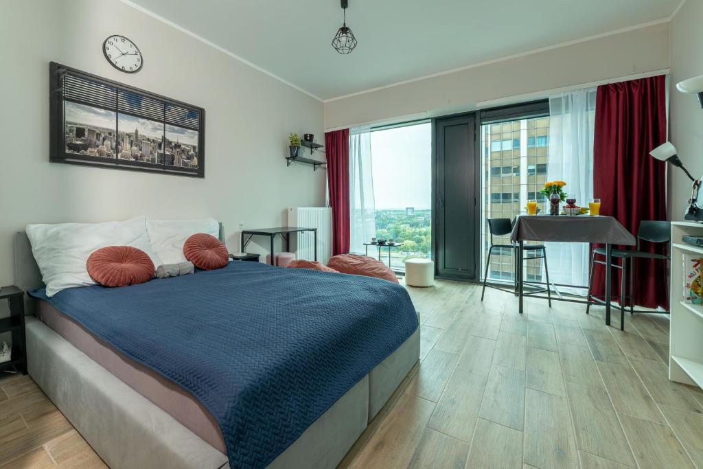 a bedroom with a bed and a table and a balcony at Sky tower space in Katowice