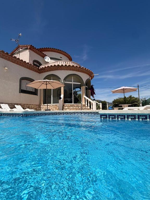 a large swimming pool with blue water in front of a house at Amarella Costa Dorada - Alojamientos privados en villa mediterránea con amplia piscina y zonas BBQ in Les tres Cales
