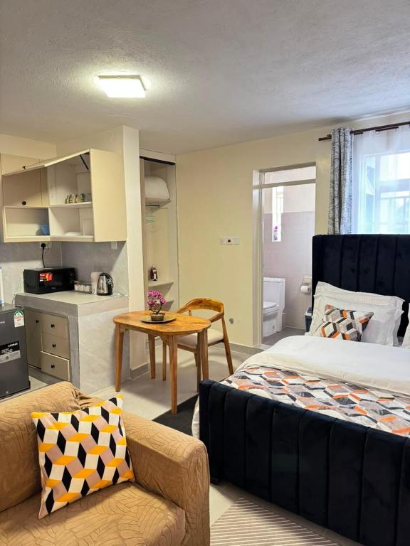 a bedroom with a bed and a table and a kitchen at Sunrise Hills BNB in Ngong