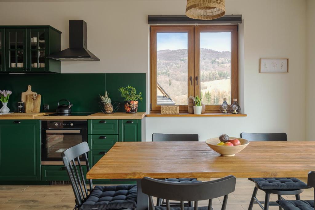 a kitchen with green cabinets and a wooden table with chairs at Widokówka in Wetlina