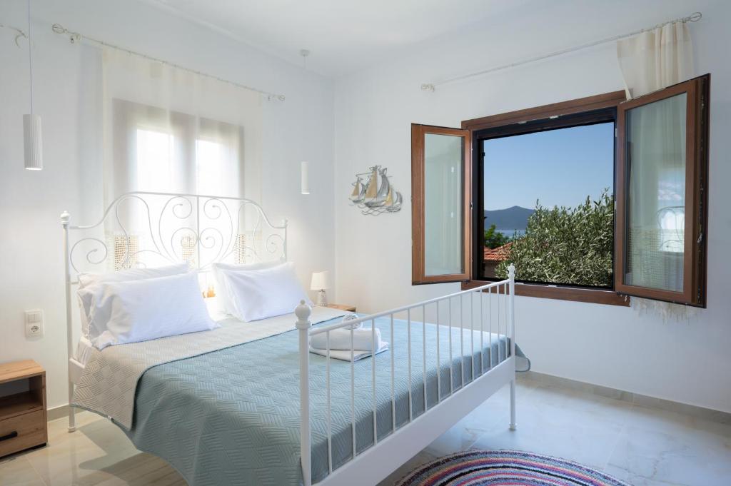 a white bedroom with a bed and a window at Lenaki House in Ayía Kiriakí