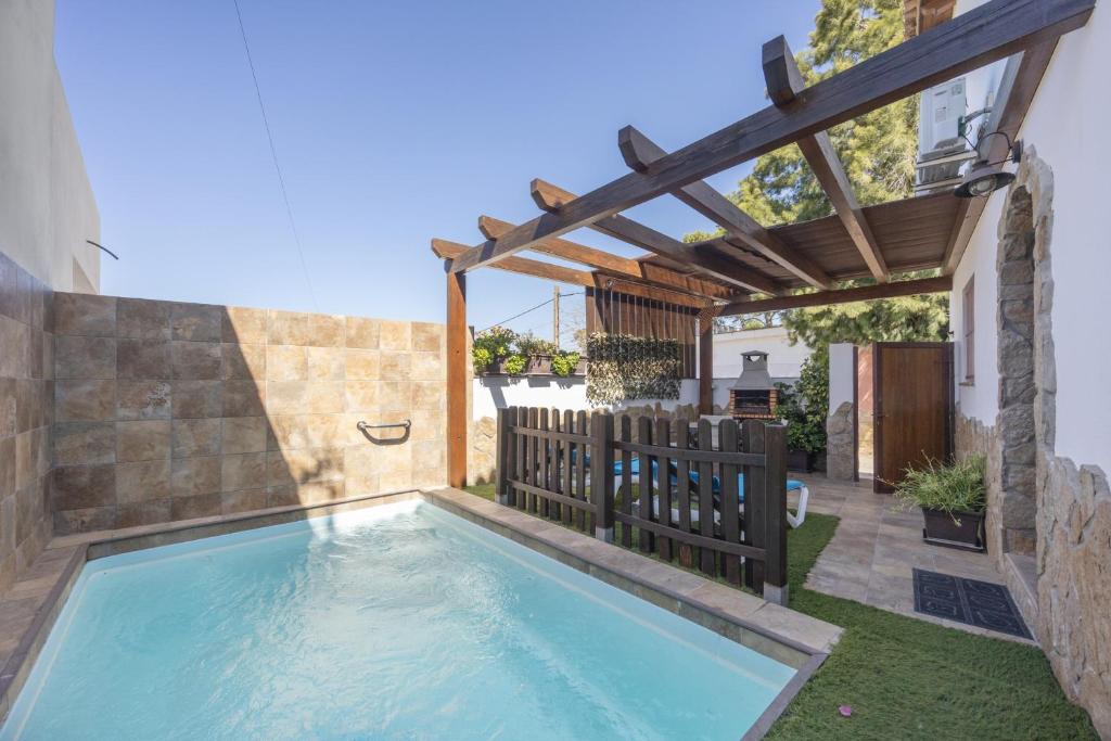 a swimming pool in a backyard with a wooden pergola at Casa El Duque Zaira in Vejer de la Frontera