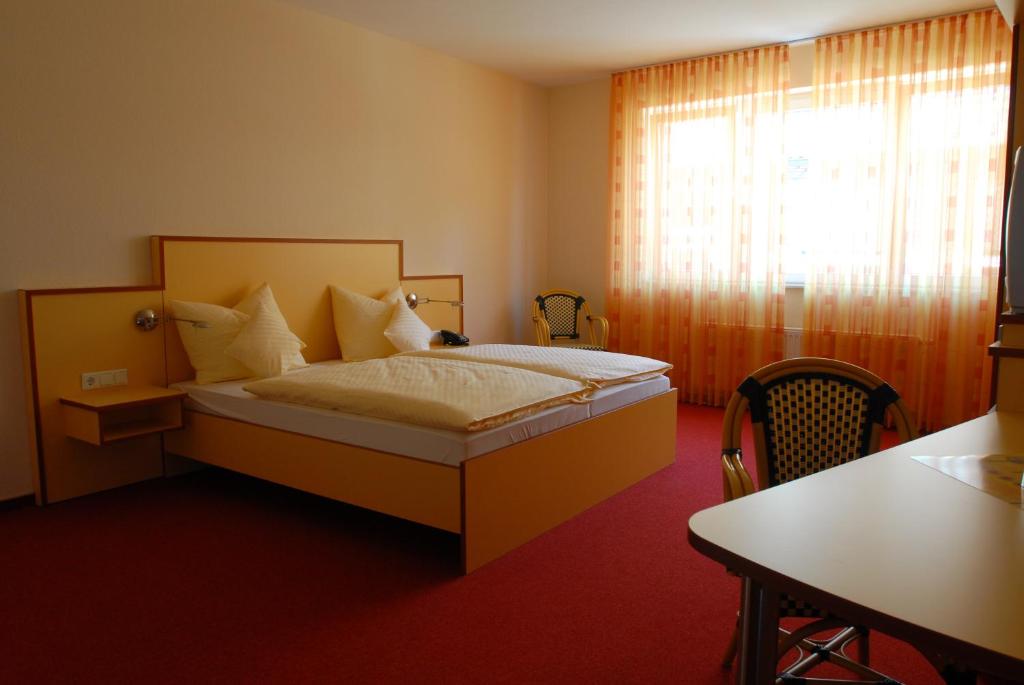 Schlafzimmer mit einem Bett, einem Tisch und einem Fenster in der Unterkunft Hotel Am Pan in Emmerich