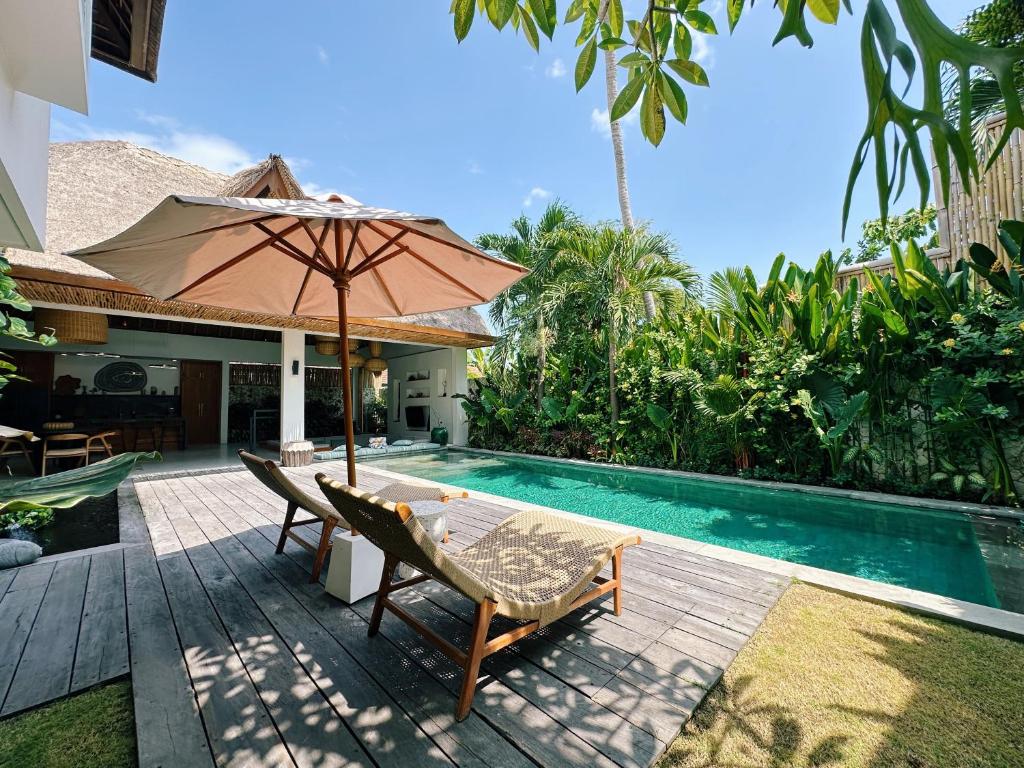a patio with an umbrella and chairs next to a swimming pool at Villa Caz a Bali in Canggu
