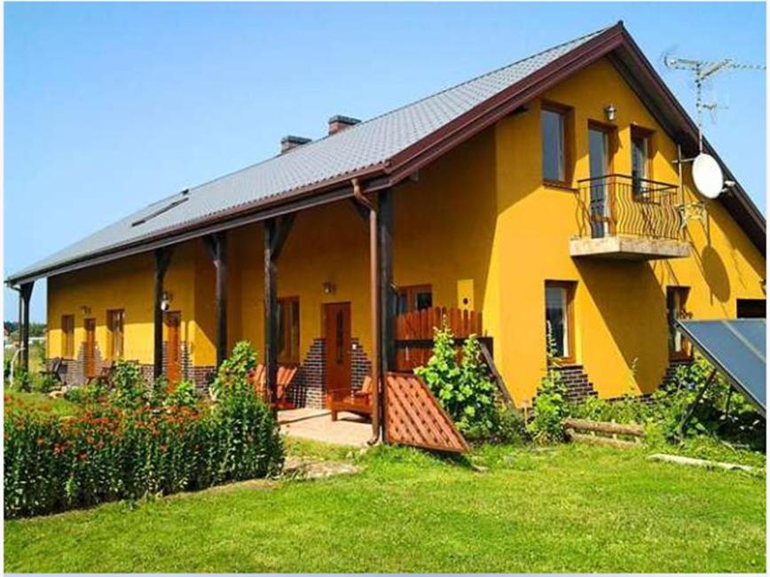Casa amarilla con porche y balcón en Gaski Na Fali, en Gąski