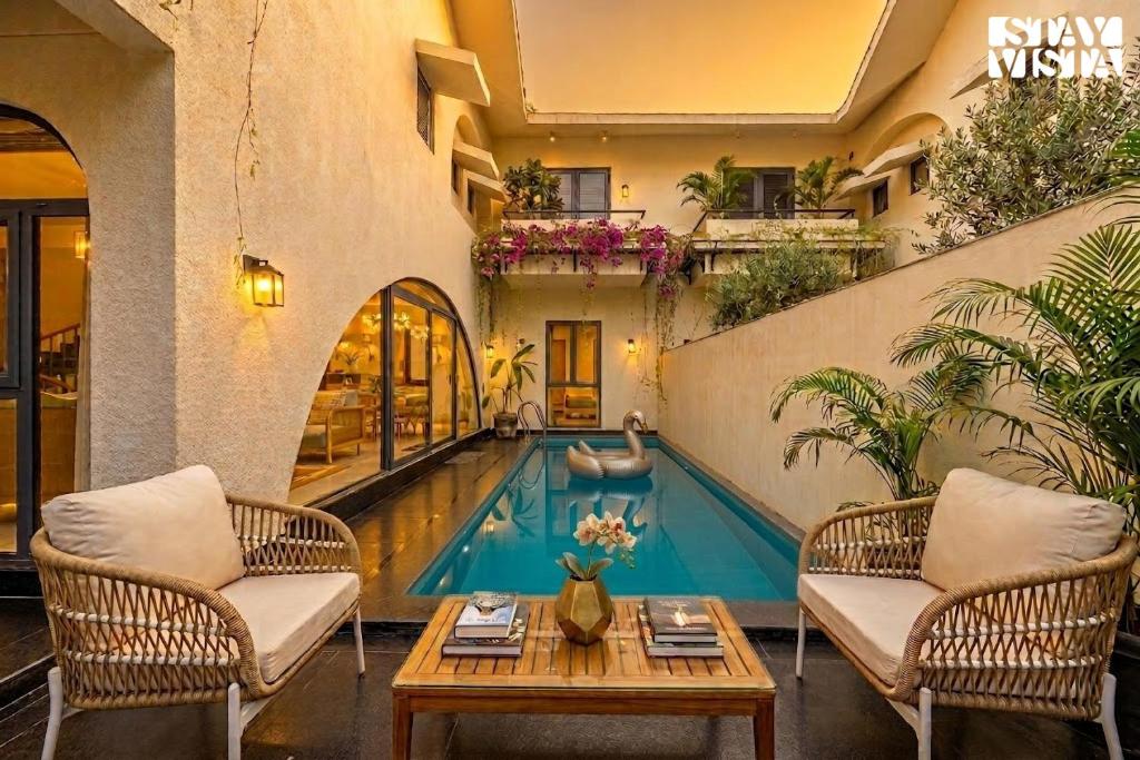 a pool in the middle of a house with chairs and a table at StayVista at Casa Roma - Private Pool in Siolim