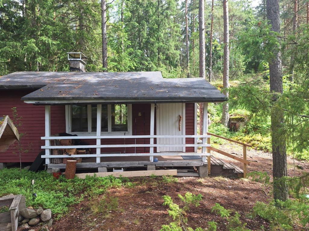 a small red house with a porch in the woods at Kalliotupa in Haapakylä
