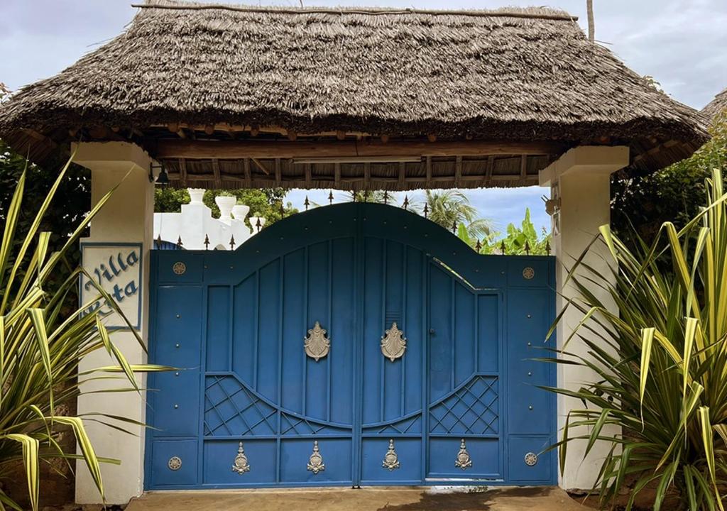 a blue garage door with a thatched roof at Villa Rita in Gede