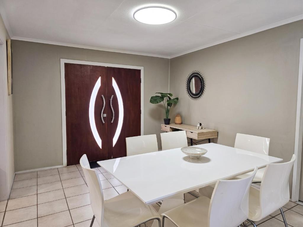 a dining room with a white table and white chairs at The Pine Rest - Spacious & Central Haven in Brendale