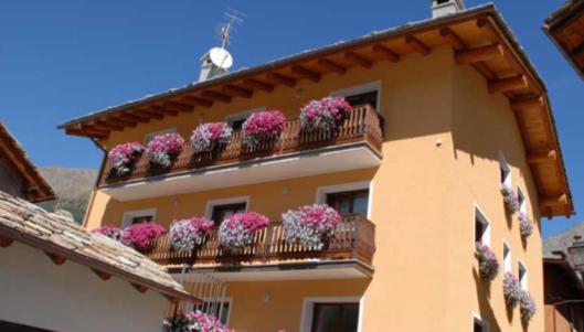 un edificio con cajas de flores en el balcón en Residence Au Vieux Grenier, en Cogne