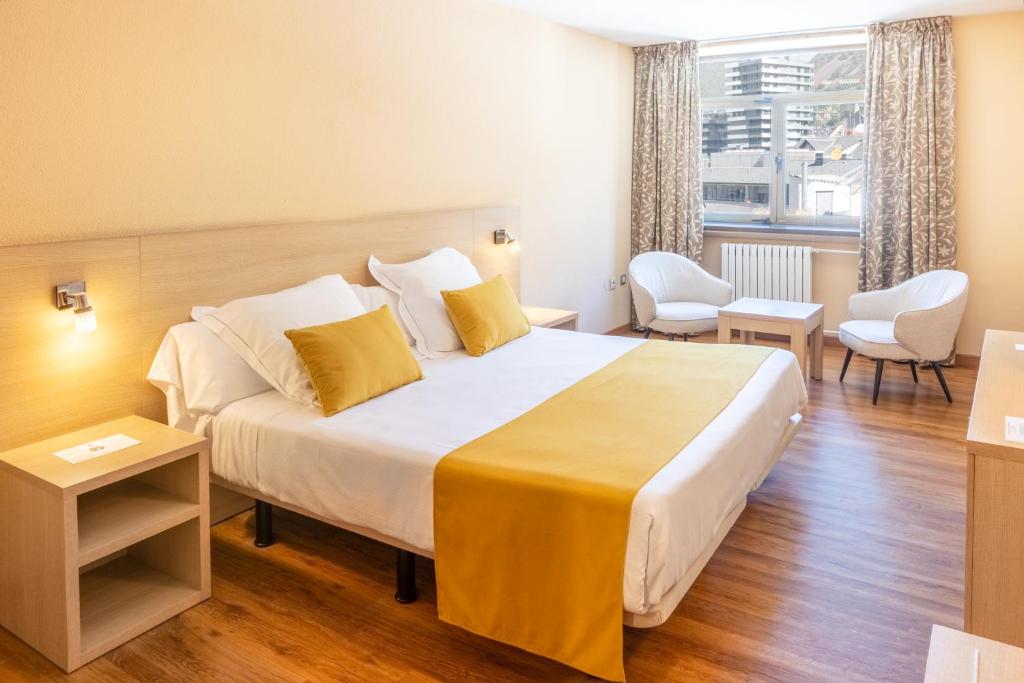 ein Hotelzimmer mit einem großen Bett und gelben Kissen in der Unterkunft Hotel Panorama in Andorra la Vella