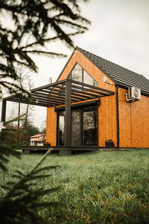 a wooden house with a black roof at Rajsco - domek nad Jeziorem Budzisławskim in Tręby Stare