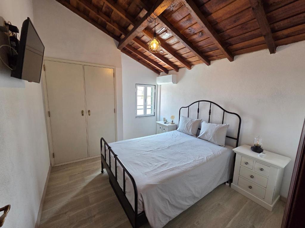 a bedroom with a bed with white sheets and a wooden ceiling at Casa Centro Montargil in Montargil