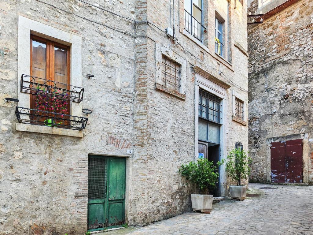 a stone building with a green door and a balcony at Il Chiostro di Ribot in Lugnano in Teverina