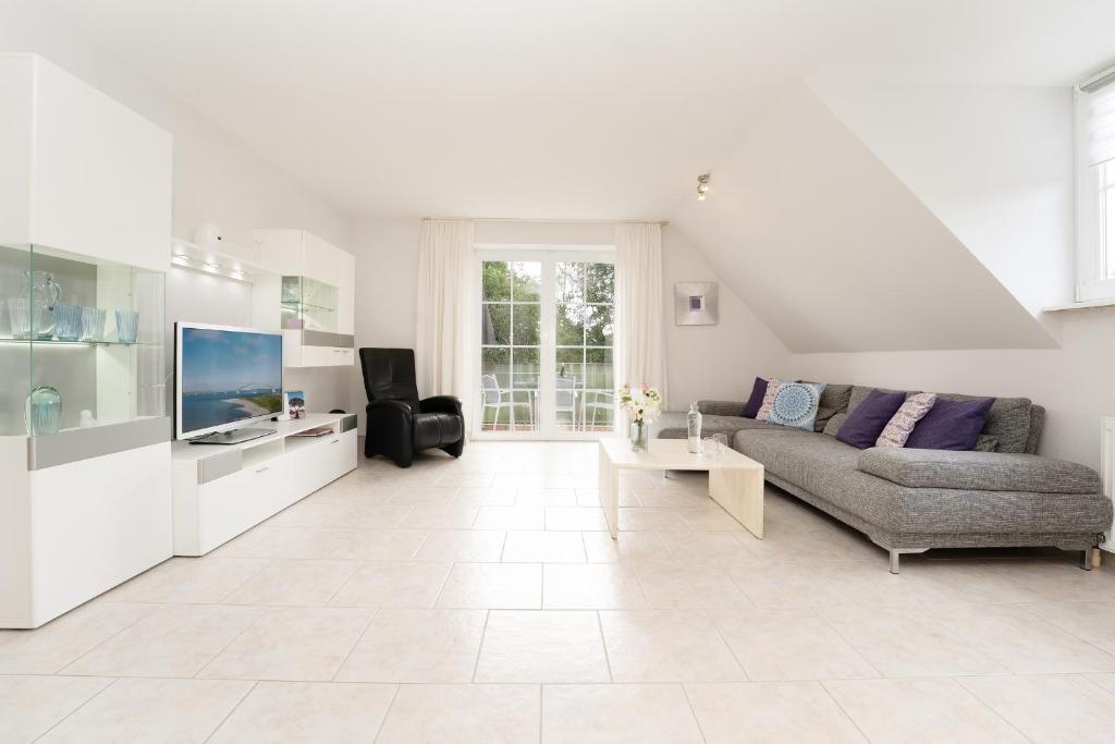 a white living room with a couch and a tv at Meerzeit Fehmarn in Wulfen auf Fehmarn