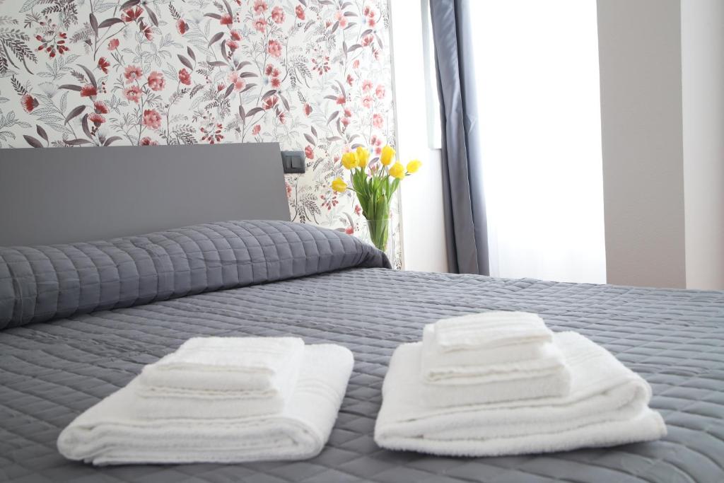a bed with three towels on it with a vase of flowers at La Torretta in Savona