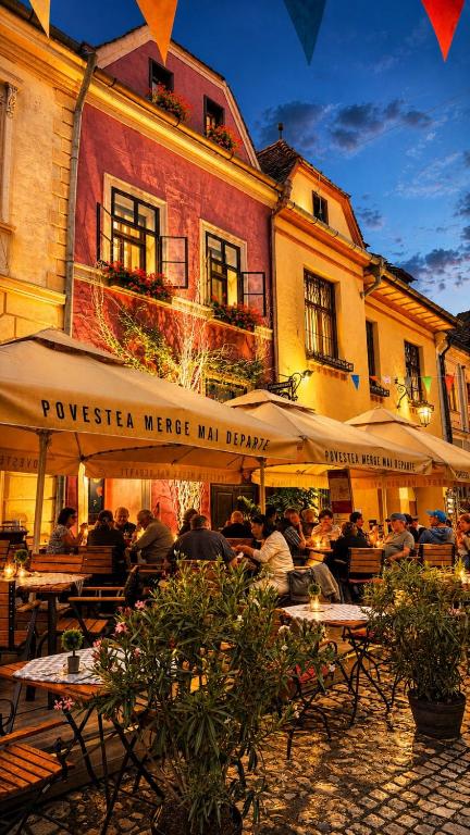 a group of people sitting at tables in front of a building at Casa Kuhn in Sighişoara