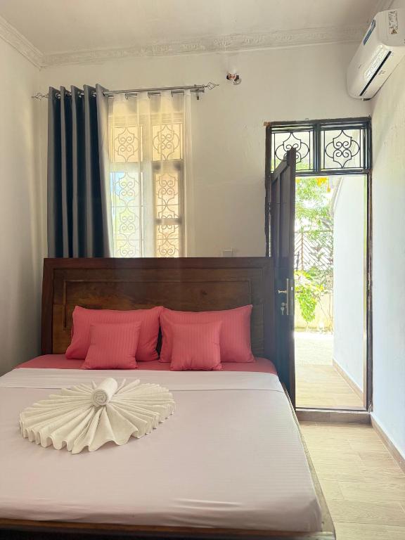 a bedroom with a large bed with pink pillows at Ebruli Guest House in Nungwi