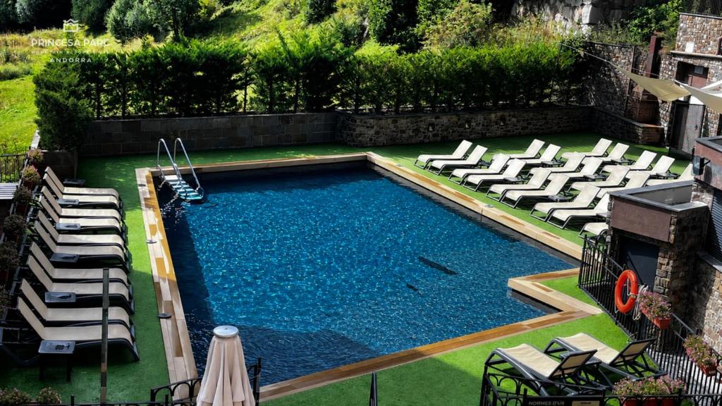 a swimming pool with lounge chairs in a backyard at Hotel Princesa Parc in Arinsal