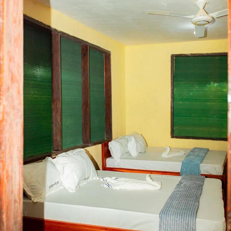 two beds in a room with two windows at Camp seleu in Dar es Salaam