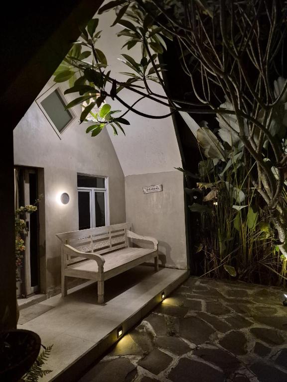 a bench sitting on a patio with a plant at Mulyanus Hotel by Calli Rooms in Wirolegi