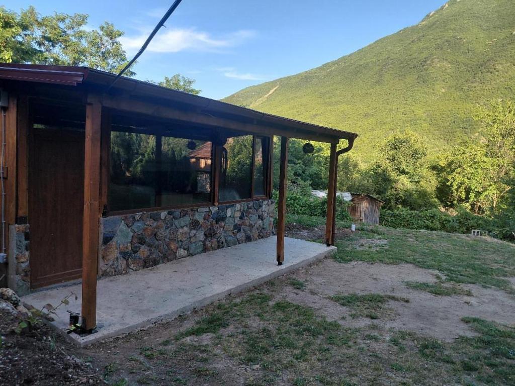 a small cabin with a stone wall and a mountain at ILIS House Matka Canyon - 2 in Skopje