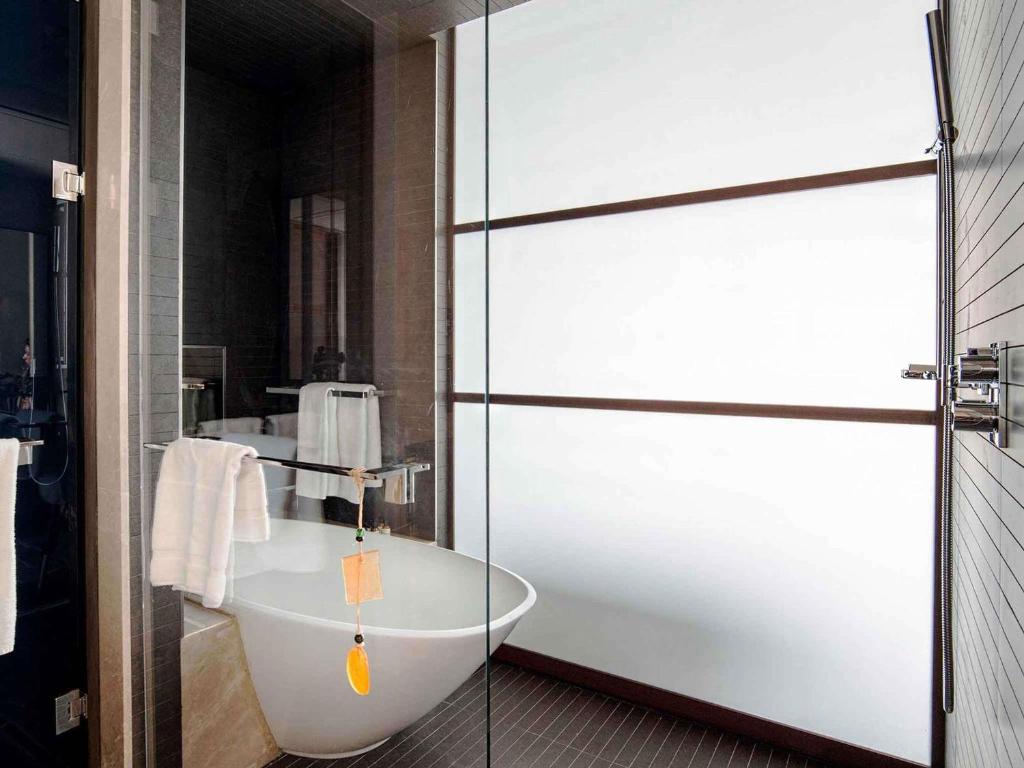 a bathroom with a bath tub and a glass door at Fairmont Quasar Istanbul Hotel in Istanbul