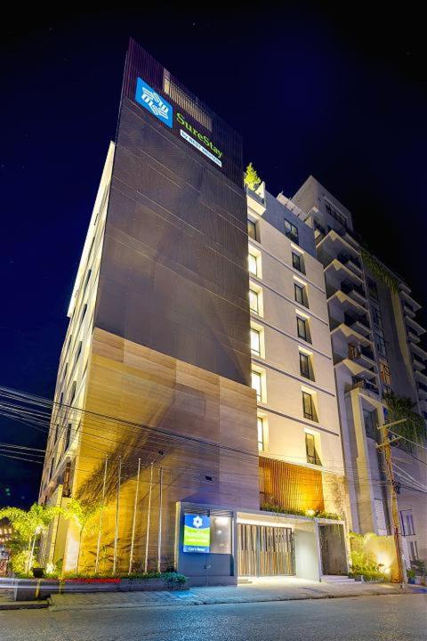 a tall building with a sign on it at night at SureStay by Best Western in Cox's Bazar