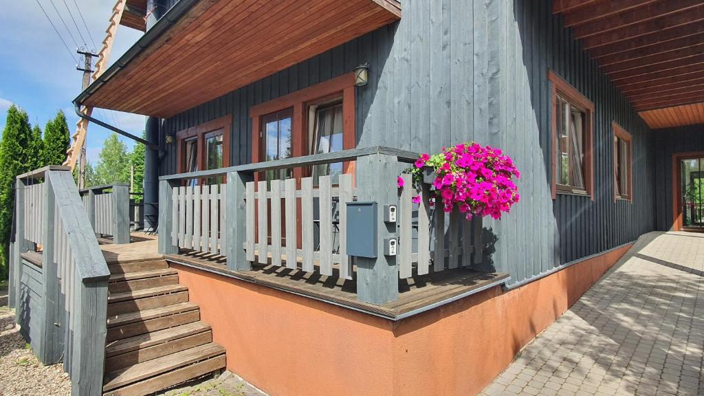 a house with a balcony with pink flowers on it at Ežerėlių sodyba in Ažuluokesa